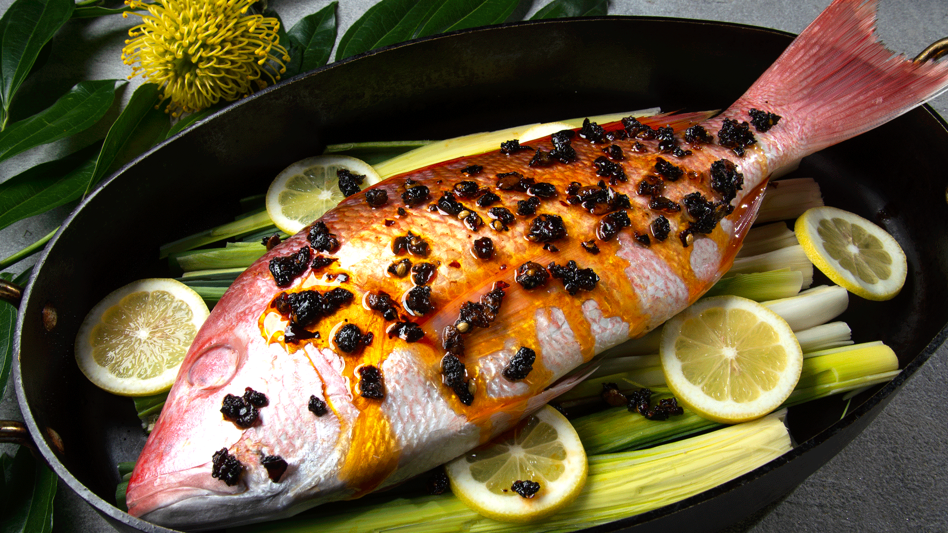 Whole red snapper with oo’mämē marinade in roasting pan on leeks and lemon slices. #myoomame