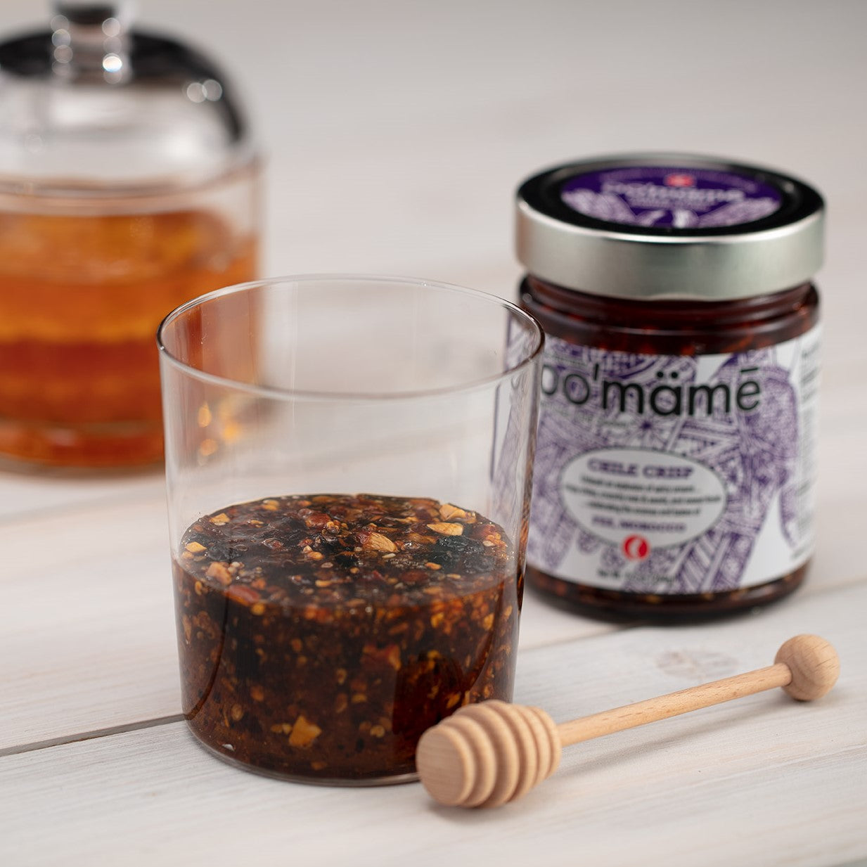 Glass with honey and Moroccan oo’mämē, jar of Moroccan oo’mämē, jar of honey comb and honey twirler.