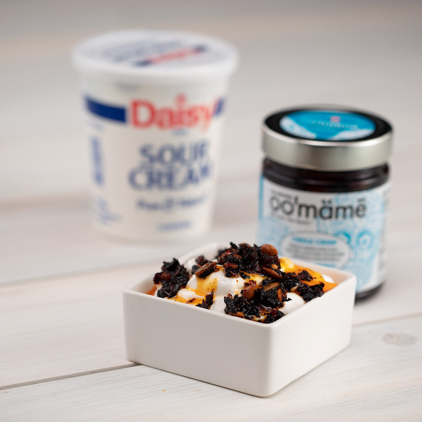 Square white dish with sour cream topped with Mexican oo’mämē, oo’mämē jar and container of sour cream