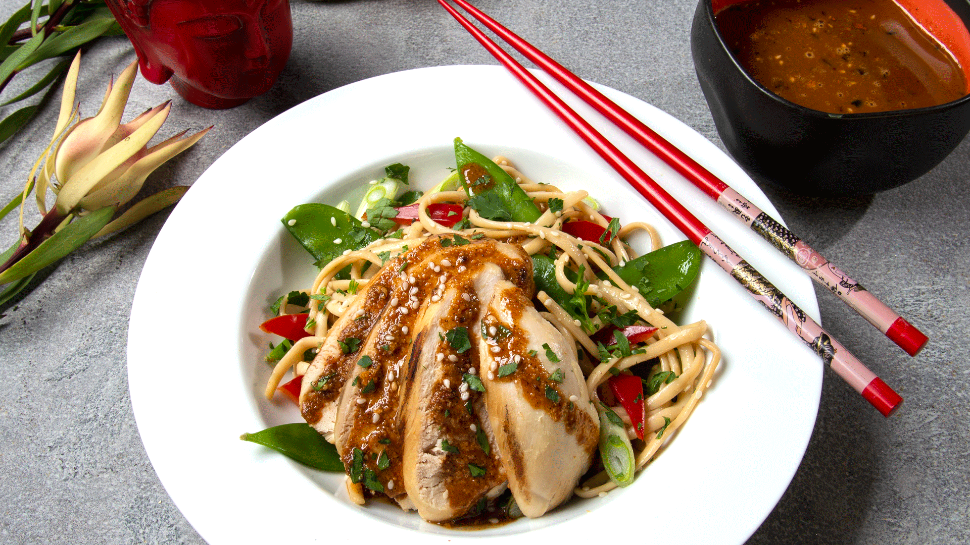 white bowl with noodles, chicken, snow peas, oo’mämē peanut sauce, with chopsticks and flower #coldsesamenoodles