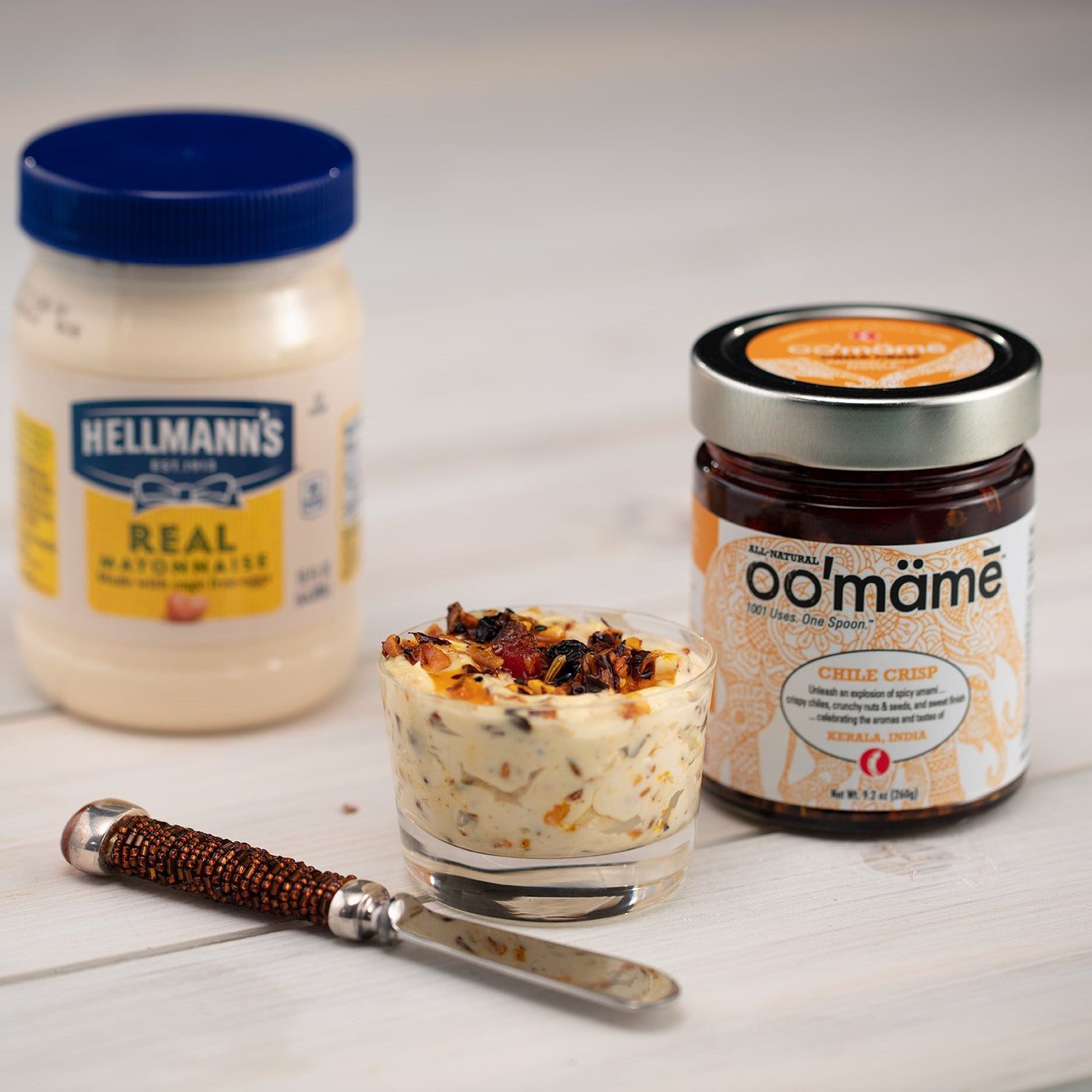Glass dish with Indian oo’mämē mayo, small knife, jar of Indian oo’mämē Chile Crisp and jar of mayonnaise. 