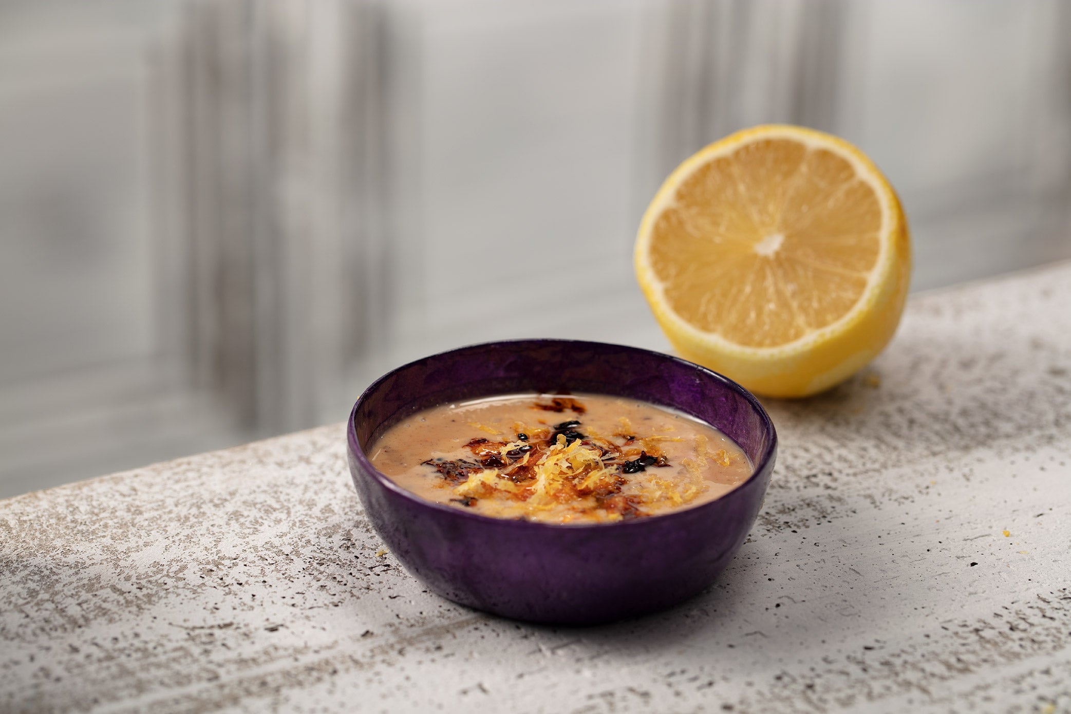 purple bowl with lemon tahini oo’mämē dressing and half a lemon