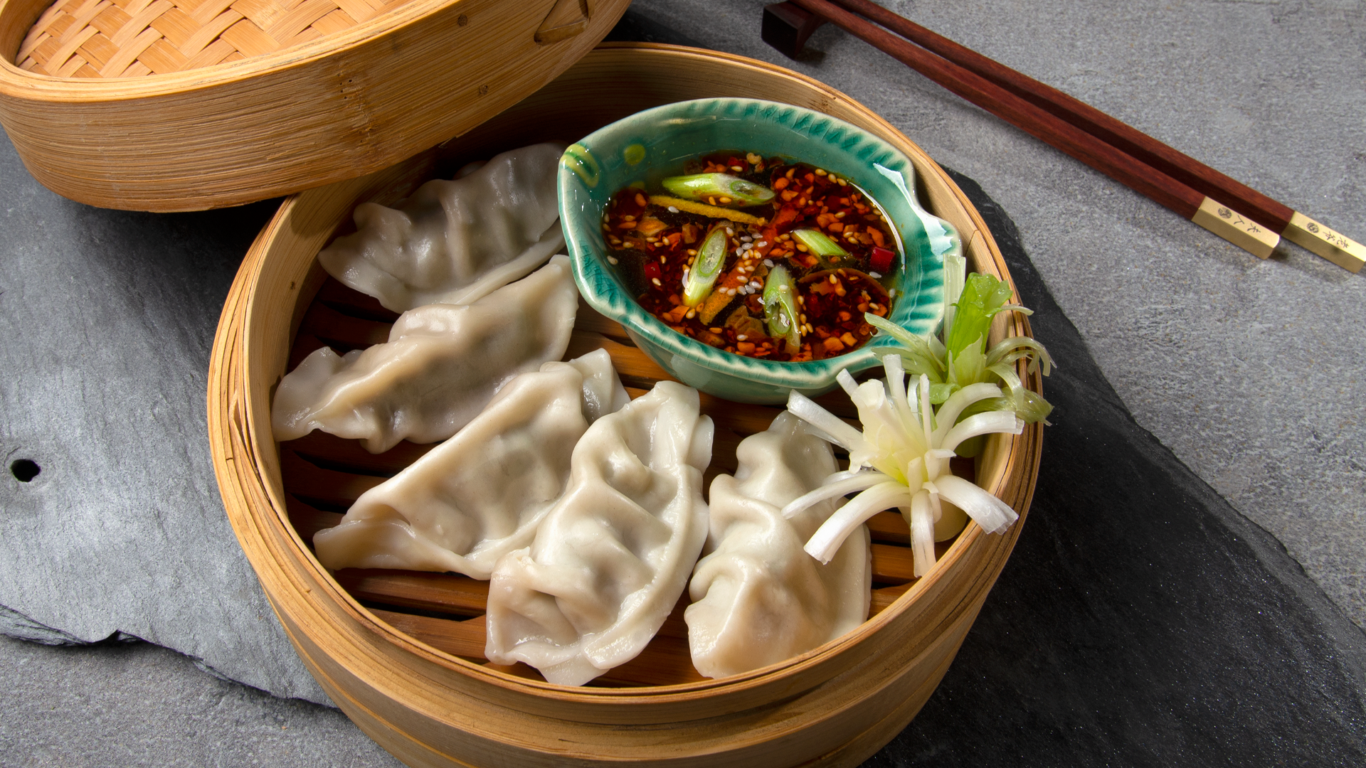 Bamboo steamer with steamed potstickers and bowl of dipping sauce with chopsticks #dumplings #myoomame