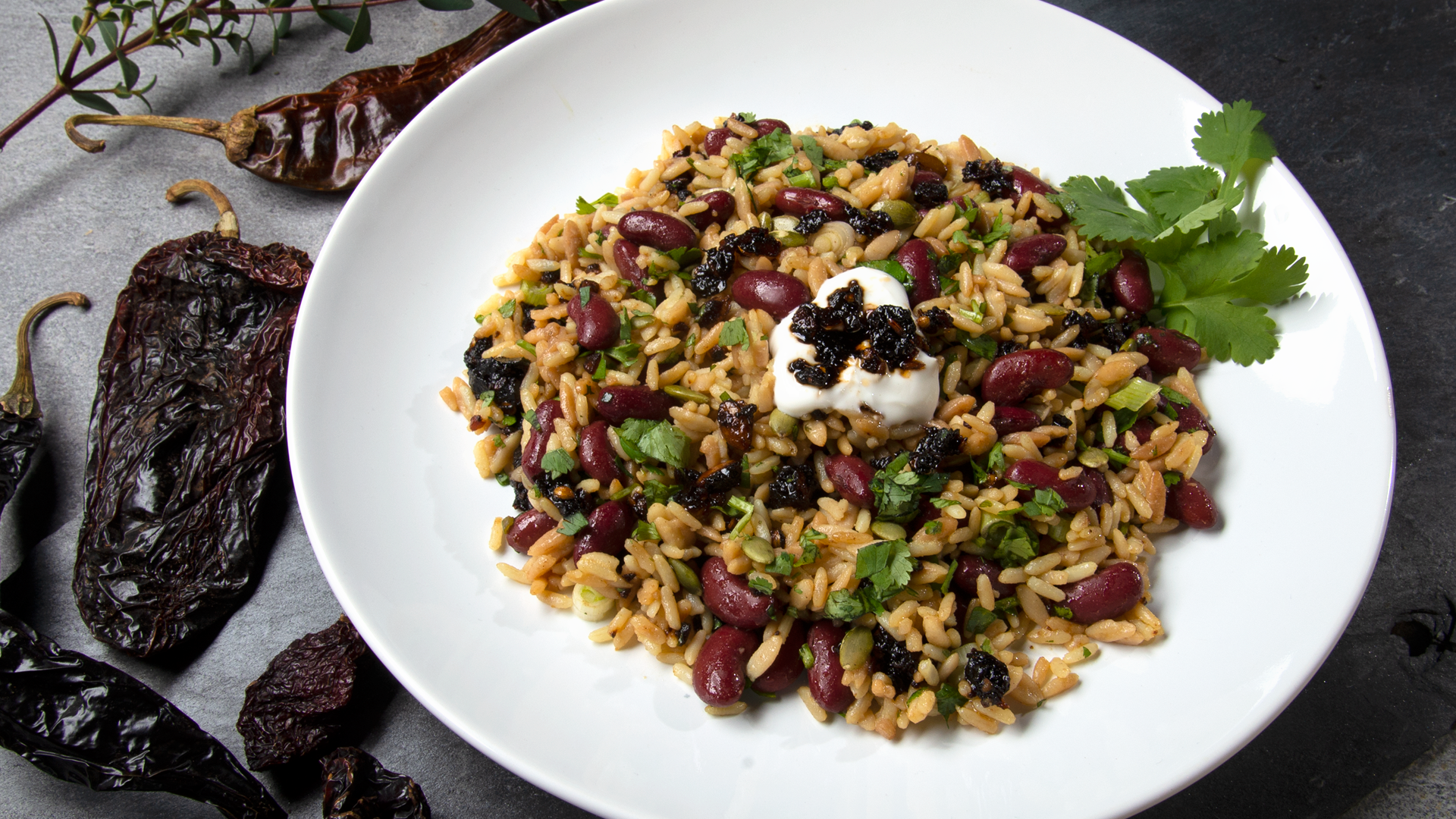 White plate with red beans and seasoned rice with oo’mämē and cilantro. Dried chiles. #myoomame