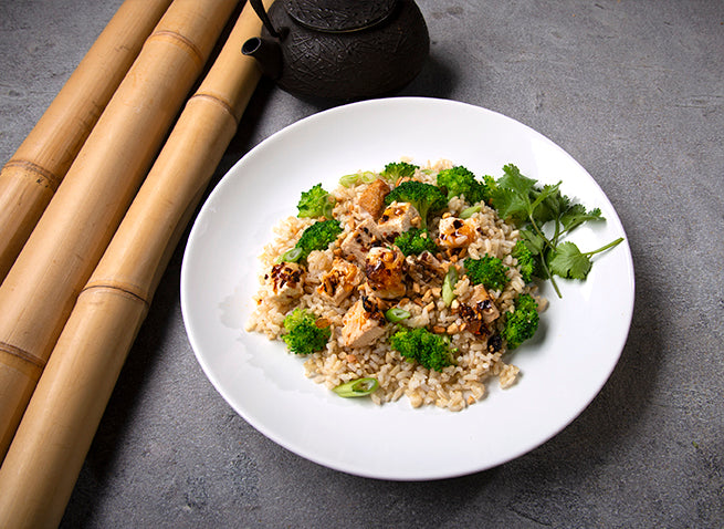 Broccoli and Tofu on white plate with umami chili crisp, bamboo and tea pot