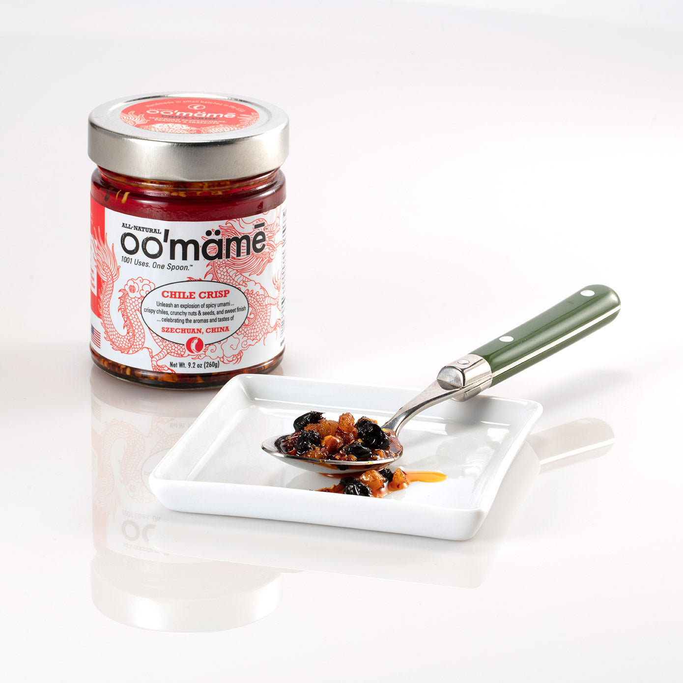 Jar of oo’mämē Chinese Chile Crisp with a spoonful of oo’mämē