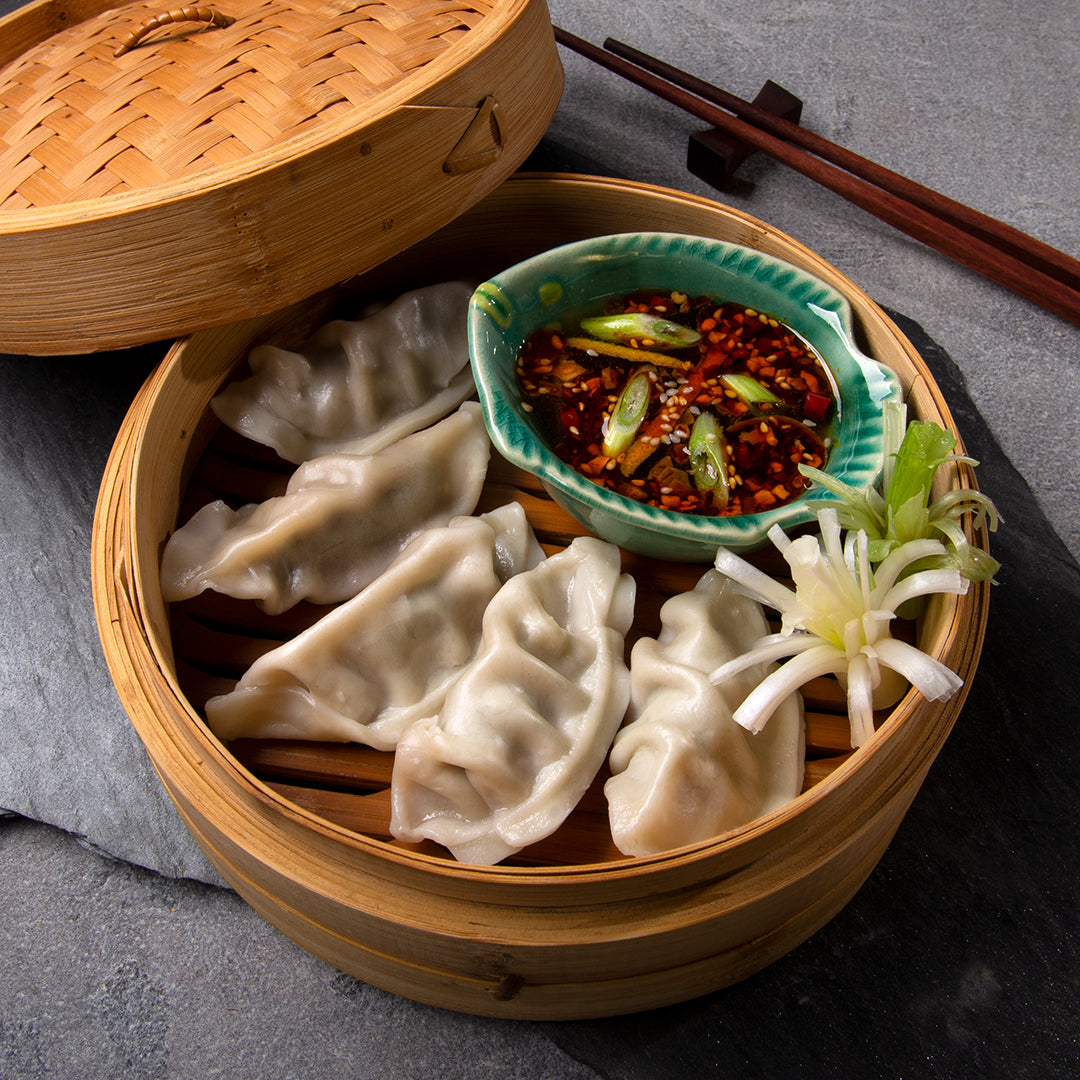 Bamboo steamer with steamed potstickers and bowl of dipping sauce with chopsticks #dumplings #myoomame