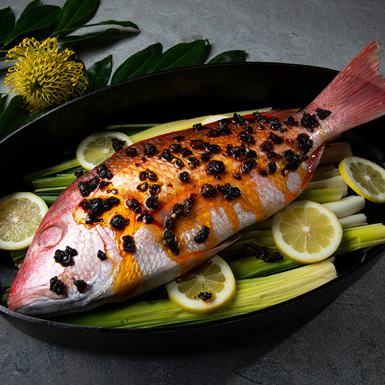 Whole red snapper with oo’mämē marinade in roasting pan on leeks and lemon slices. #myoomame